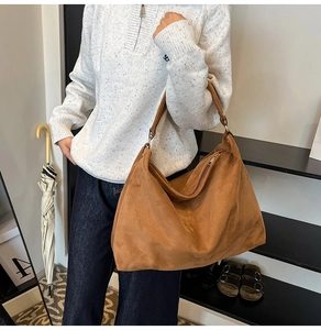 Detail of caramel suede tote bag featuring a thick shoulder strap and zipper closure