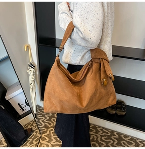 Detail of tan suede shoulder bag with ruched side and button accent on model