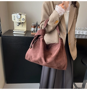 Detail of reddish-brown suede tote bag with a large knot shoulder strap for autumn style