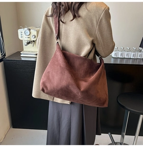 Close-up of brown suede minimalist shoulder bag with soft texture and wide strap