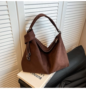 Close-up of the dark brown suede hobo bag shoulder strap knot and metal ring detail