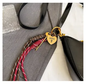Detail of woven crescent bag strap with golden heart lock and key charms