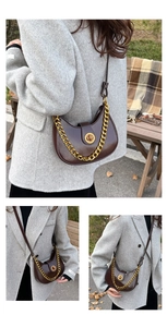 Detail of dark brown saddle bag featuring a bold gold chain and round metallic buckle