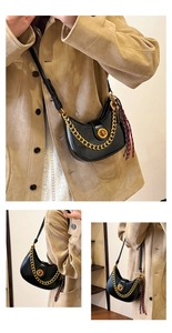 Detail of black crescent hobo bag with gold chain, twist lock, and woven tassel accent
