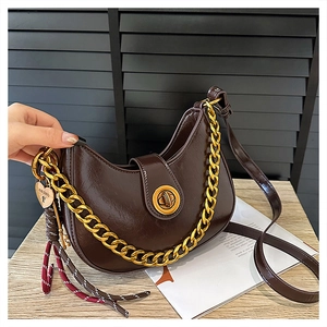 Detail of hobo bag featuring a gold round twist lock and chunky chain decoration