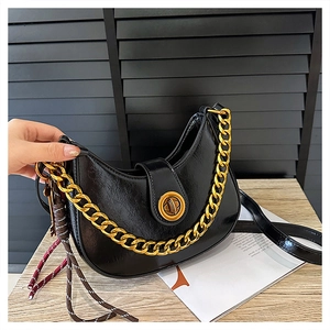 Close-up of black crescent bag featuring shiny oil-wax leather and gold chain handle