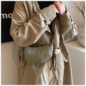 Detail of grey-green frosted crescent bag with dark brown strap and plush charm decoration