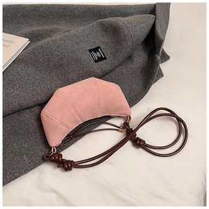 Detail of pink croissant bag in matte suede texture with dark brown knotted rope strap