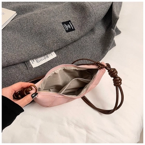 Detail view of pink frosted crossbody bag with twisted rope strap and inner zipper pocket