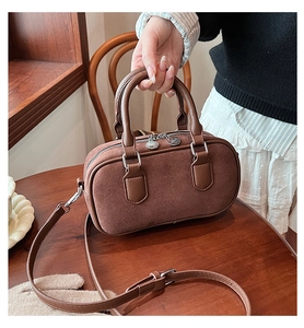 Vue détaillée du sac bowling en daim marron avec double poignée et bandoulière amovible