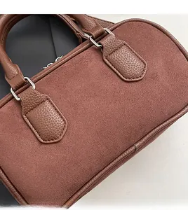 Close-up of brown suede and litchi leather textures on a vintage boston handbag