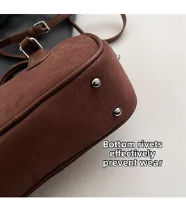 Detail view of brown suede bag featuring metal bottom rivets to prevent surface wear