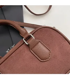 Detail of silver hardware links and contrast leather textures on a brown vintage pillow bag