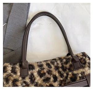 Detail of leopard print plush tote bag with durable brown leather handle attachment