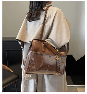 Detail of a brown transparent PVC tote bag with leather inner pouch and bell charm