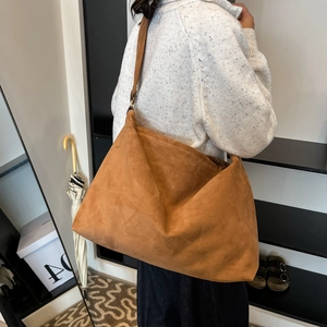 Minimalist brown matte shoulder bag for women shown as worn by model in a soft suede finish