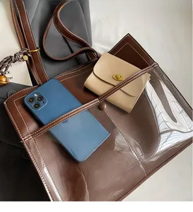 Detail of vintage brown leather tote bag with transparent PVC pocket showing capacity