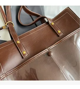 Detail of reinforced handles and gold rivets on a dark brown faux leather tote bag
