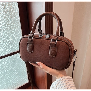 Détail du sac bowling marron vintage montrant les textures de cuir mat et grainé