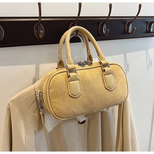 Détail du sac bowling en daim jaune avec design cylindrique et ferrures en métal argenté