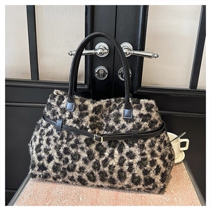 Close-up of leopard print tote bag texture with black leather handles and buckle detail