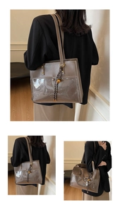 Detail of a brown leather and PVC tote bag featuring metal rivets and tassel charms