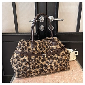 Detail of plush leopard print tote bag with brown leather handles and metal buckle accent