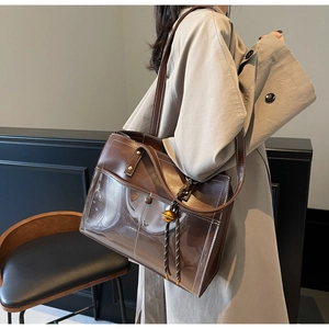 Detail of retro brown leather tote with clear PVC pocket and gold bell charm on model