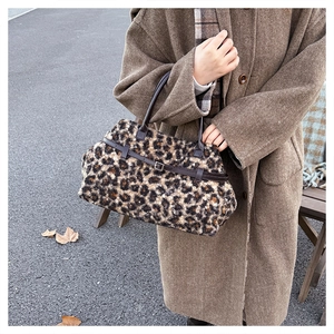 Detail shot of leopard print plush tote bag with brown leather handles and buckle strap