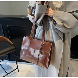 Detail of a brown tote bag featuring PVC transparent outer layer and faux leather interior