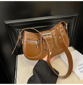 Detail view of vintage caramel brown crescent bag with glossy texture and zipper buckles