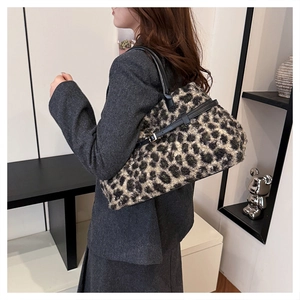 Detailed side view of leopard print plush tote bag with black leather handle on model