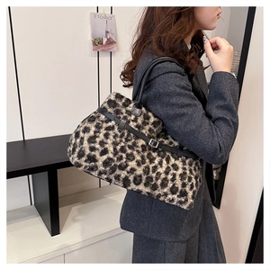 Detail of leopard print tote bag with black leather handle and golden metal buckle