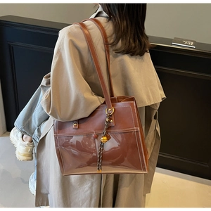 Detail of vintage brown leather tote bag with contrast stitching and golden ball charm