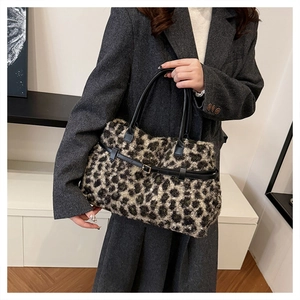 Close-up of leopard print faux fur tote bag with black leather straps on a model