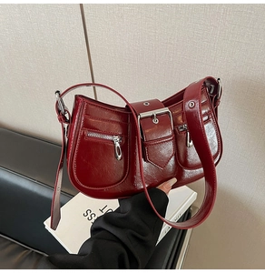 Detailed macro view of dark red vintage underarm bag with zipper pockets and buckle