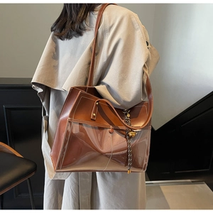 Detail of a brown patchwork tote bag with glossy finish and white contrast stitching