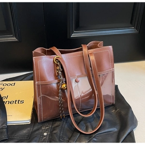 Detail of vintage brown PU leather and transparent PVC tote bag with decorative charm