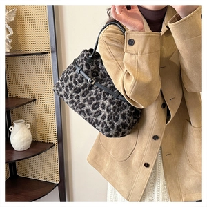 Detailed texture of plush leopard print tote bag with black leather handle and buckle decor