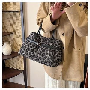 Close-up of leopard print faux fur tote bag with black leather straps and gold buckle detail