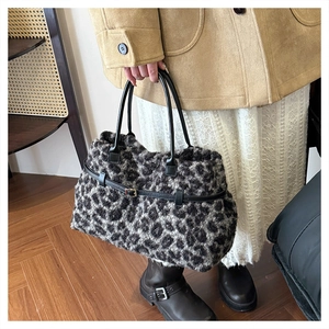 Detail of leopard print faux fur tote bag with black leather straps and metal buckle accent