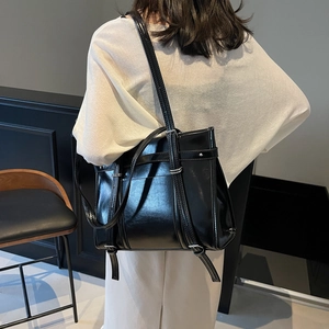 Large black glossy leather tote bag with silver buckles and studs shown on a model