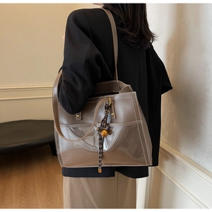 Detail of brown leather and PVC tote with contrast stitching and metal ball drawstring