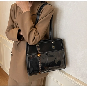 Detail of black tote bag with white contrast stitching and decorative bell pendant