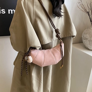Pink quilted crescent shoulder bag with knotted brown strap and plush pompom charm