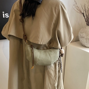 Green crescent crossbody bag in matte suede finish with woven rope strap on a model