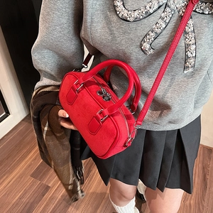 Sac Boston rouge mini avec poignées et bandoulière présenté dans un cadre de vie réel