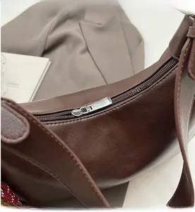 Detailed close-up of smooth silver metal zipper on dark brown crescent hobo bag