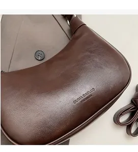 Close-up of deep brown hobo bag showing pebbled leather texture and embossed logo detail