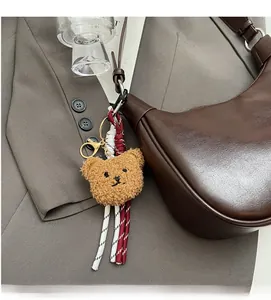 Detail of cute teddy bear charm on deep brown leather shoulder bag with gold hardware